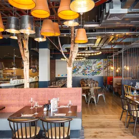Zizzi Coventry, vibrant dining space with high ceilings and natural light, hanging decor and artistic wall art.