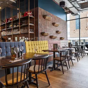 Zizzi Coventry, vibrant dining space with high ceilings and natural light, hanging decor and artistic wall art.