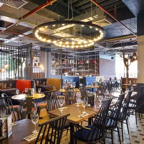 Zizzi Coventry, vibrant dining space with high ceilings and natural light, hanging decor and artistic wall art.