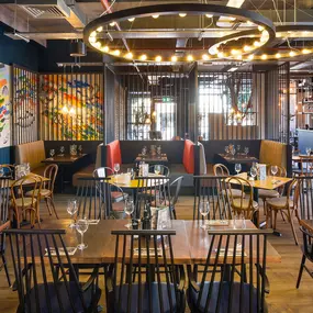 Zizzi Coventry, vibrant dining space with high ceilings and natural light, hanging decor and artistic wall art.