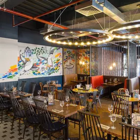 Zizzi Coventry, vibrant dining space with high ceilings and natural light, hanging decor and artistic wall art.