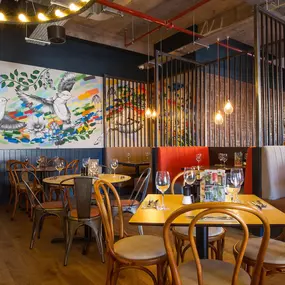 Zizzi Coventry, vibrant dining space with high ceilings and natural light, hanging decor and artistic wall art.