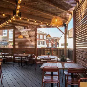 Exterior view of Zizzi St Albans terrace dining under wooden canopy and fairy lighting.
