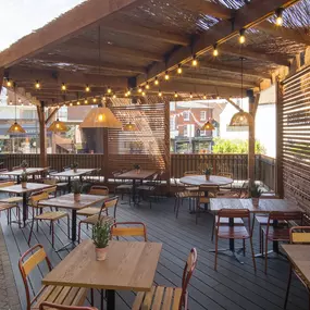 Exterior view of Zizzi St Albans terrace dining under wooden canopy and fairy lighting.