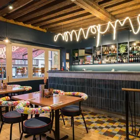 Interior view of Zizzi Maidstone, featuring vibrant wall murals, hanging foliage and bold mixed seating styles.