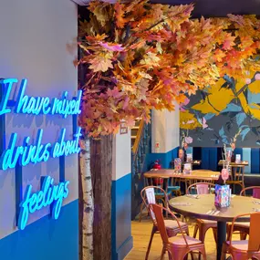 Interior view of Zizzi Maidstone, featuring vibrant wall murals, hanging foliage and bold mixed seating styles.