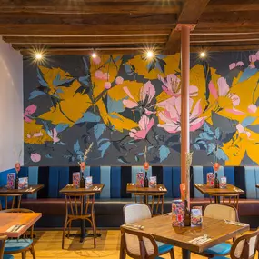 Interior view of Zizzi Maidstone, featuring vibrant wall murals, hanging foliage and bold mixed seating styles.