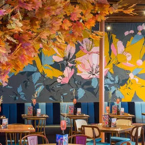 Interior view of Zizzi Maidstone, featuring vibrant wall murals, hanging foliage and bold mixed seating styles.