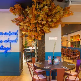Interior view of Zizzi Maidstone, featuring vibrant wall murals, hanging foliage and bold mixed seating styles.