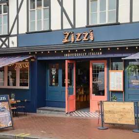 Exterior view of Zizzi Maidstone, located in a historic Tudor building and features an outside dining area protest by awnings.