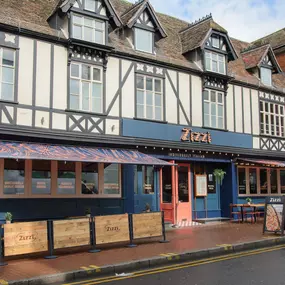 Exterior view of Zizzi Maidstone, located in a historic Tudor building and features an outside dining area protest by awnings.