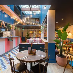 Interior view of Zizzi Maidstone, featuring vibrant wall murals, hanging foliage and bold mixed seating styles.