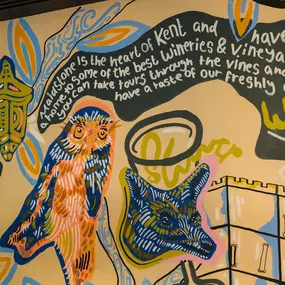 Interior view of Zizzi Maidstone, featuring vibrant wall murals, hanging foliage and bold mixed seating styles.