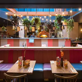 Interior view of Zizzi Maidstone, featuring vibrant wall murals, hanging foliage and bold mixed seating styles.