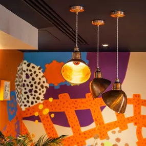 Zizzi - Glasgow Princes Square, vibrant interior with banquet seating and gallery views, and orange foliage creating an inviting atmosphere.