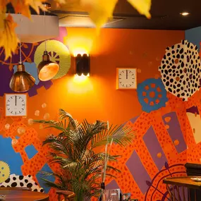 Zizzi - Glasgow Princes Square, vibrant interior with banquet seating and gallery views, and orange foliage creating an inviting atmosphere.