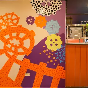 Zizzi - Glasgow Princes Square, vibrant interior with banquet seating and gallery views, and orange foliage creating an inviting atmosphere.