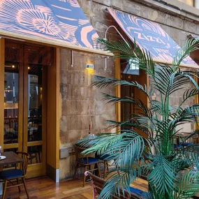 Zizzi - Glasgow Princes Square, vibrant interior with banquet seating and gallery views, and orange foliage creating an inviting atmosphere.