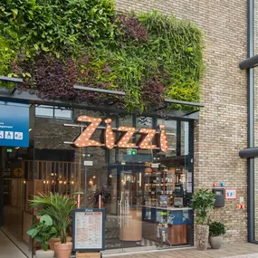 Zizzi Leicester Fosse Park, exterior entrance with greenery wall and outdoor seating.
