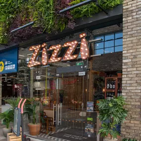 Zizzi Leicester Fosse Park, exterior entrance with greenery wall and outdoor seating.