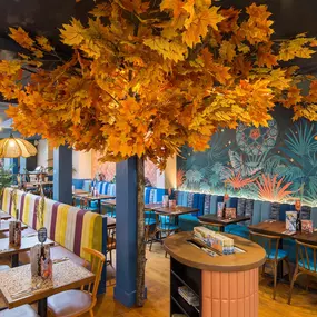 Zizzi Exeter, modern interior with hanging ceiling decor and foliage, and classy wall murals surround the restaurant walls.