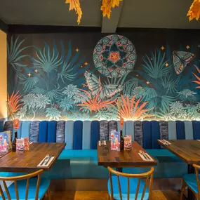Zizzi Exeter, modern interior with hanging ceiling decor and foliage, and classy wall murals surround the restaurant walls.