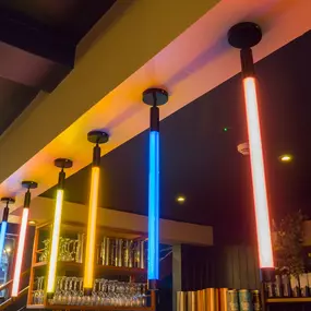 Zizzi Exeter, modern interior with vibrant neon decor and hanging ceiling decor and foliage, creating a warm dining room experience.