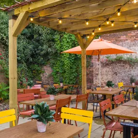 Zizzi Exeter, sheltered, charming outdoor dining space with greenery and wooden pergolas providing shade.