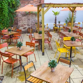Zizzi Exeter, sheltered, charming outdoor dining space with greenery and wooden pergolas providing shade.