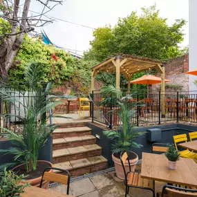 Zizzi Exeter, sheltered, charming outdoor dining space with greenery and wooden pergolas providing shade.