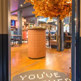 Zizzi Exeter, modern interior with hanging ceiling decor and foliage, and classy wall murals surround the restaurant walls.