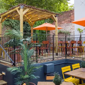 Zizzi Exeter, sheltered, charming outdoor dining space with greenery and wooden pergolas providing shade.