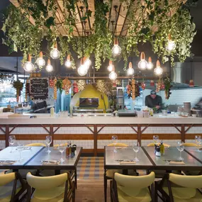 Zizzi Leeds Birstall, interior view of bright, open dining with colourful seating and large windows.