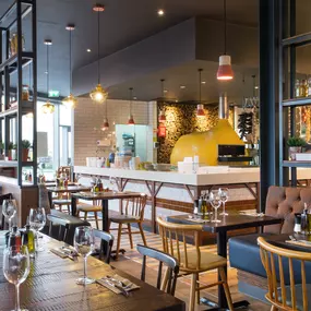 Zizzi Leeds Birstall, interior view of bright, open dining with colourful seating and large windows.