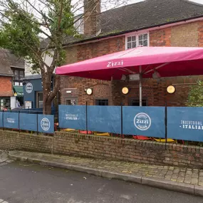 Exterior view of Zizzi Sevenoaks outdoor dining area protected by umbrellas.