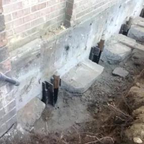 Foundation settling repair with concrete piers and steel brackets installed.