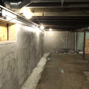 New foundation wall construction in a basement with fresh concrete.