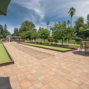 A large patio with tables and umbrellas and bocce call courts