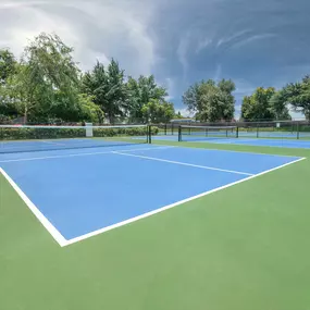 A blue and green tennis court with a net and trees