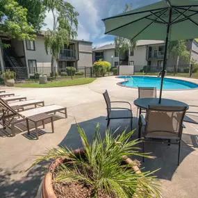 A large pool and patio with chairs and umbrellas