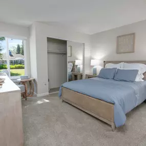 Model apartment master bedroom with a bed and a dresser and a window