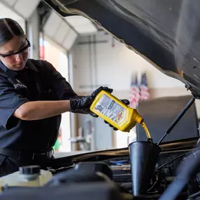 female tech pouring Pennzoil oil into car