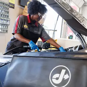 woman tech under hood of car oil change