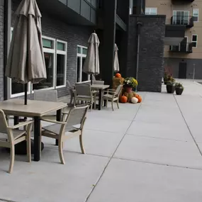 This inviting outdoor patio at Saint Therese of Corcoran features patio furniture, umbrellas, and planters with fall decorations.