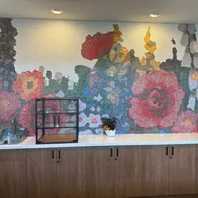 This vibrant dining area at Saint Therese of Corcoran features a stunning mosaic wall depicting a colorful floral scene.