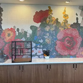 This vibrant dining area at Saint Therese of Corcoran features a stunning mosaic wall depicting a colorful floral scene.