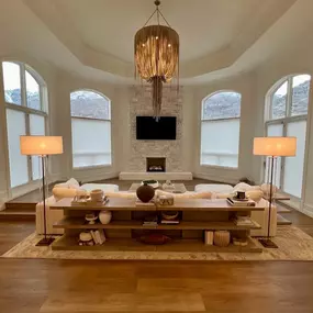 Enhance the elegance of your formal living room with custom shades from GrandView Blinds & Designs. This spacious great room showcases light-filtering shades installed on large arched windows, complementing the luxurious decor while offering light control and privacy.