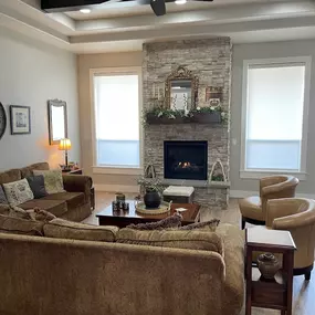 Complement your traditional living room decor with custom window shades from GrandView Blinds & Designs. These light-filtering shades provide privacy and blend seamlessly with the room's rustic elements, like the stone fireplace and wood beams.