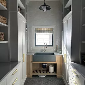 Elevate functional spaces like laundry or utility rooms with custom Roman shades from GrandView Blinds & Designs. This plaid fabric shade adds pattern and warmth, complementing the high-end finishes while providing light control and privacy.