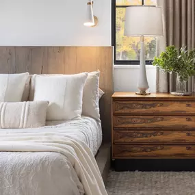 Create a serene retreat with custom drapery from GrandView Blinds & Designs. This bedroom showcases elegant window treatments providing essential light control and privacy, enhancing the cozy, modern-rustic ambiance.